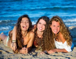 Girls group friends having fun happy lying on the beach sand sho