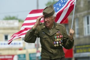 Veteran carrying the US flag and saluting